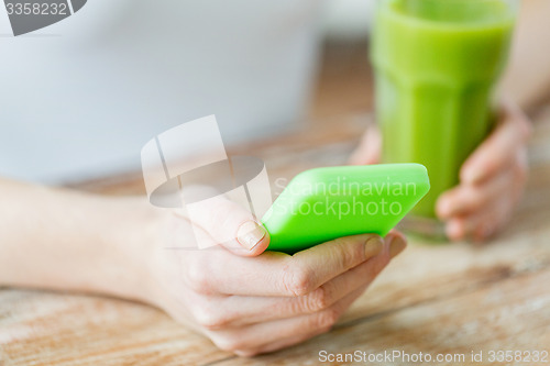 Image of close up of woman with smartphone and green juice