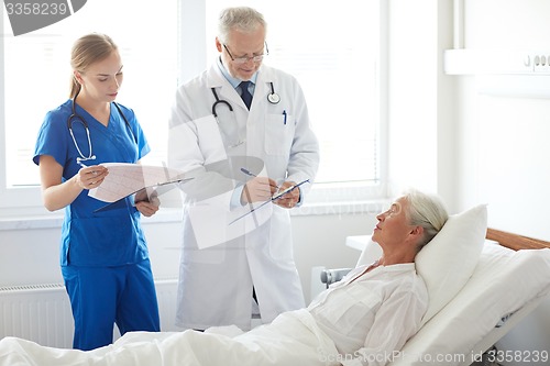 Image of doctor and nurse visiting senior woman at hospital