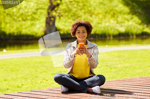 Image of happy african young woman messaging on smartphone