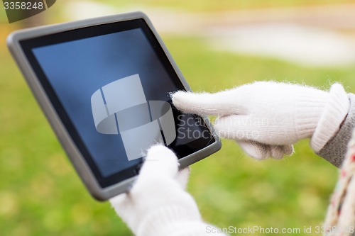 Image of hands in autumn gloves holding tablet pc outdoors