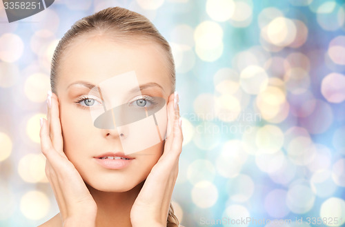 Image of beautiful young woman touching her face