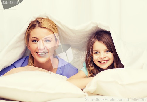 Image of mother and little girl under blanket at home