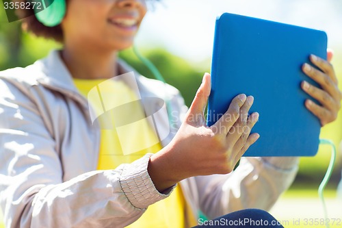 Image of happy african woman with tablet pc and headphones