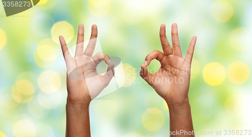 Image of two african hands showing ok sign over blue sky