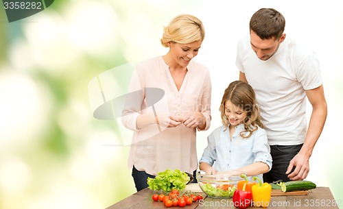 Image of happy family cooking vegetable salad for dinner