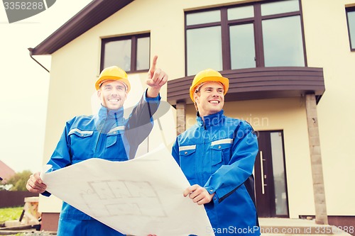 Image of smiling builders with blueprint pointing finger