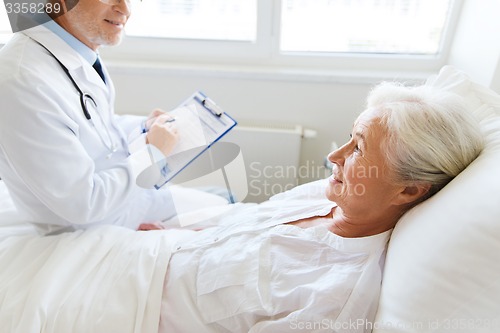 Image of senior woman and doctor with clipboard at hospital