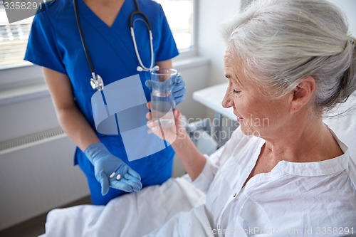 Image of nurse giving medicine to senior woman at hospital