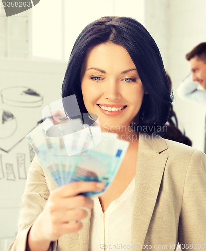 Image of happy businesswoman with cash money in office