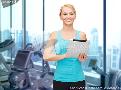 Image of smiling sporty woman with tablet pc in gym