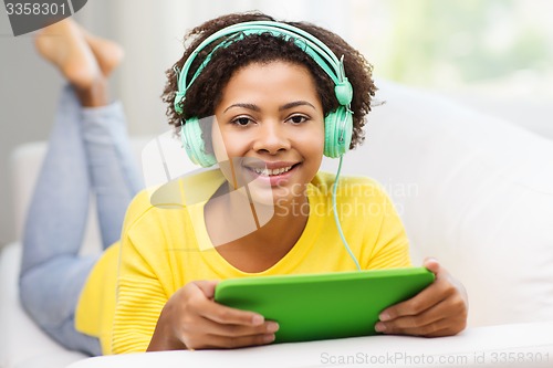 Image of happy african woman with tablet pc and headphones