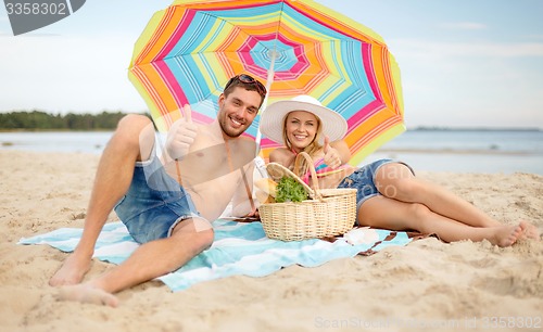 Image of couple having picnic and sunbathing on beach