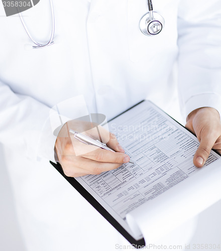 Image of male doctor holding prescription paper in hand