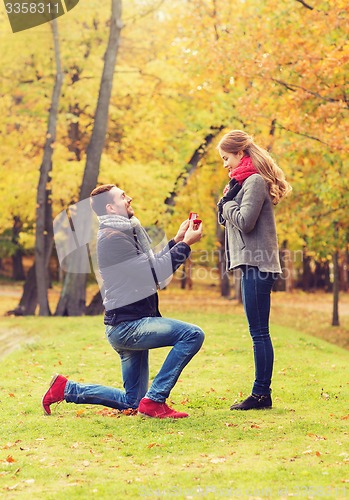 Image of smiling couple with engagement ring in gift box