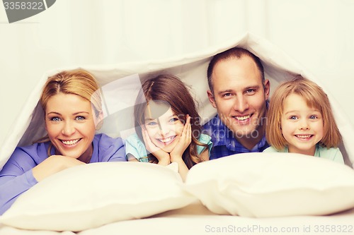 Image of happy family with two kids under blanket at home