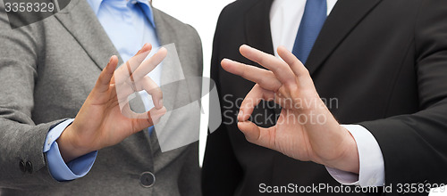 Image of businessman and businesswoman showing ok sign