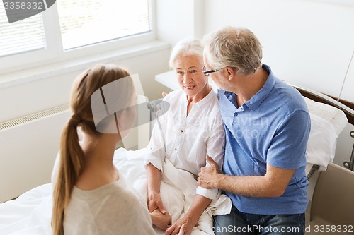 Image of happy family visiting senior woman at hospital