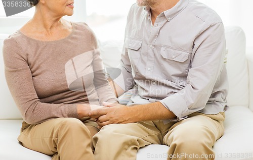 Image of close up of senior couple holding hands at home