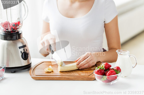 Image of close up of woman with blender chopping banana