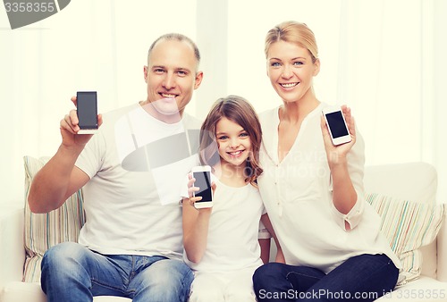 Image of parents and little girl with smartphones at home