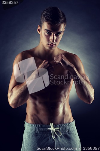 Image of young man on fighting stand over black background