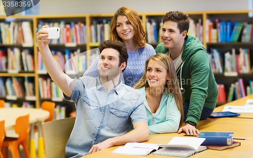 Image of students with smartphone taking selfie in library