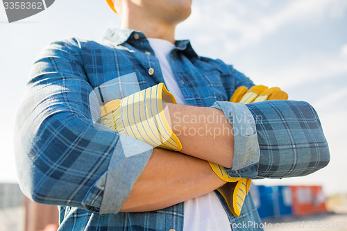 Image of close up of builder crossed hands in gloves