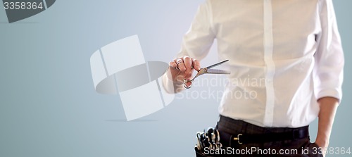 Image of close up of male stylist with scissors over blue