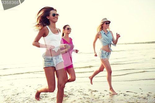 Image of group of smiling women running on beach