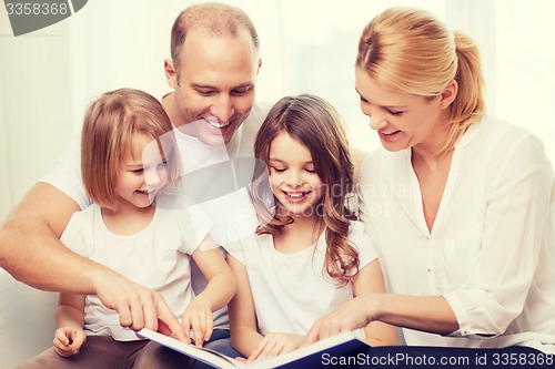 Image of smiling family and two little girls with book