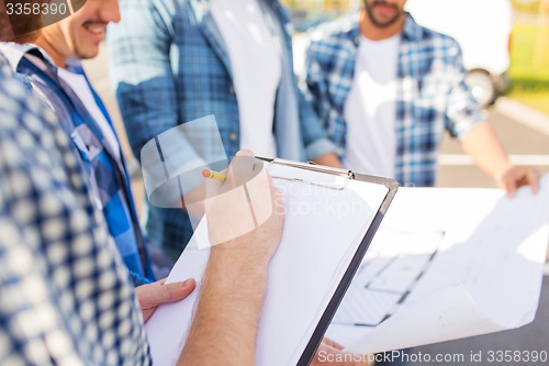 Image of close up of builders with clipboard and blueprint