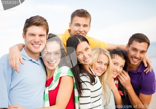Image of group of happy friends hugging on beach