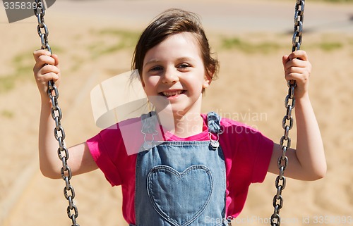 Image of happy little girl swinging on swing at playground