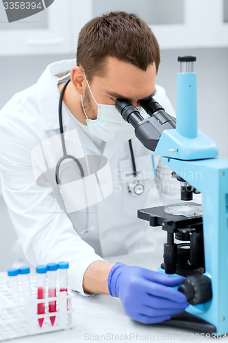 Image of young scientist looking to microscope in lab