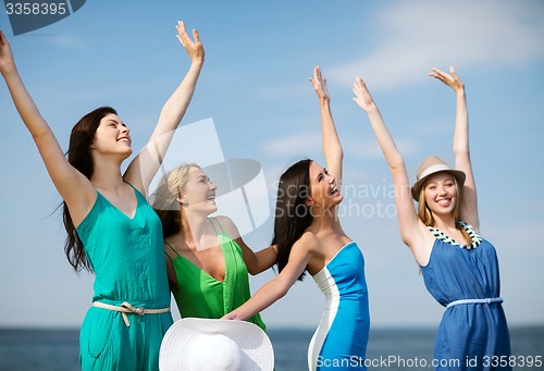 Image of girls looking at the sea with hands up