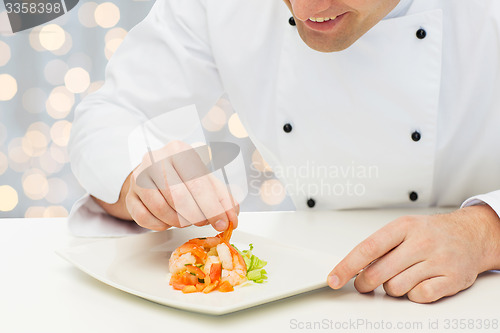 Image of close up of happy male chef cook decorating dish