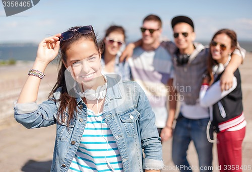 Image of teenage girl with headphones and friends outside