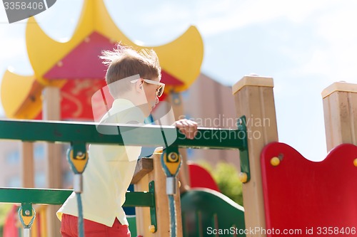 Image of happy little boy climbing on children playground