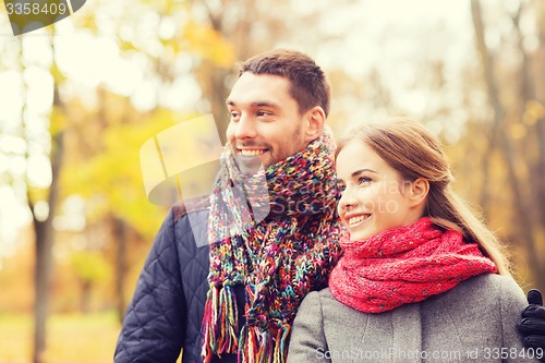 Image of smiling couple hugging on bridge in autumn park