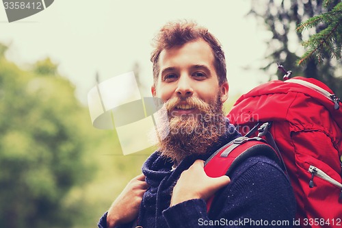 Image of smiling man with beard and backpack hiking