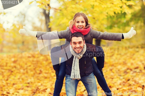 Image of smiling couple having fun in autumn park