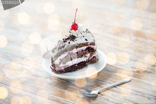 Image of piece of cherry chocolate cake on wooden table