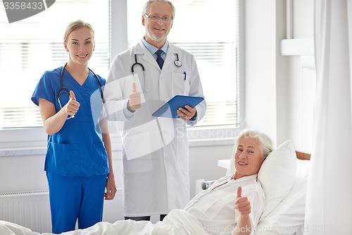 Image of doctor and nurse visiting senior woman at hospital