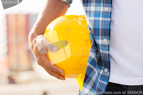 Image of close up of builder hand holding hardhat outdoors