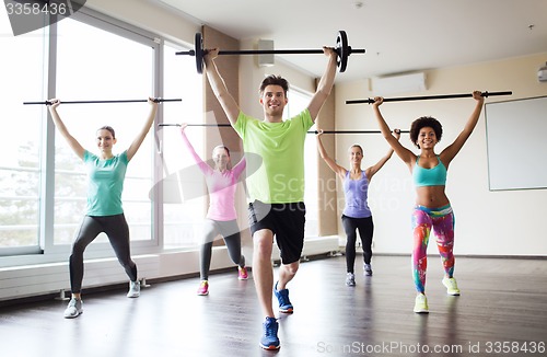 Image of group of people exercising with bars in gym