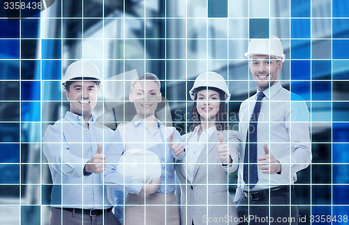 Image of happy business team in office showing thumbs up