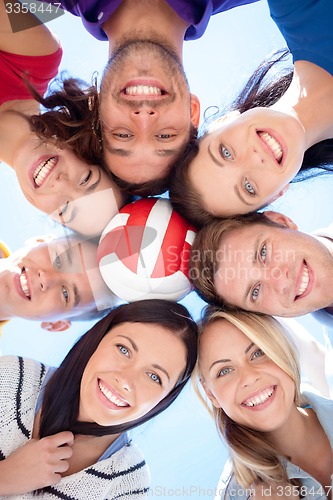 Image of smiling friends with ball in circle over blue sky