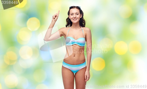 Image of happy woman in bikini swimsuit pointing finger up