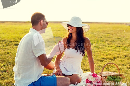 Image of smiling couple with small red gift box on picnic
