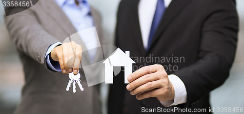 Image of businessman and businesswoman holding white house